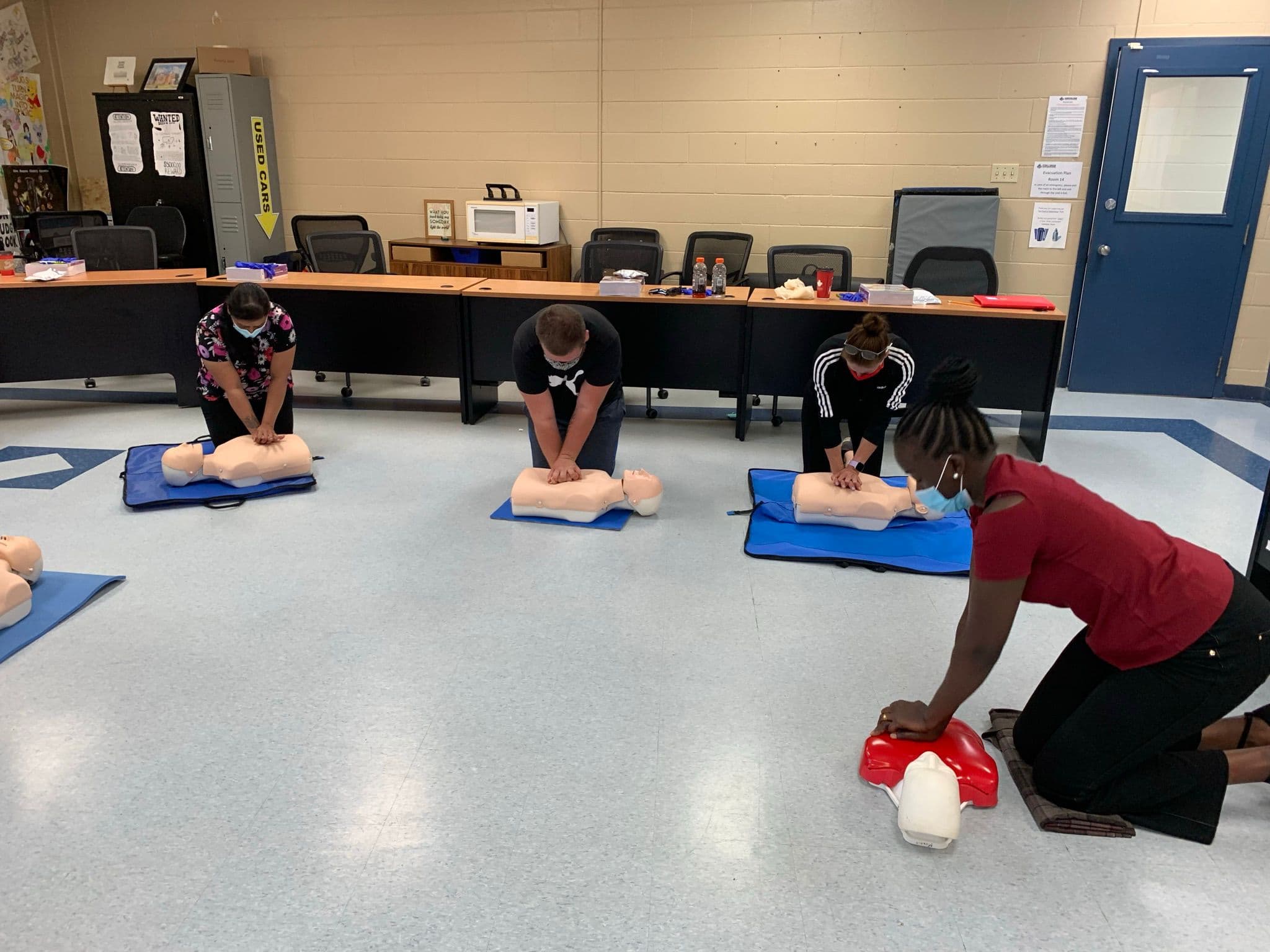 Group of participants practicing CPR chest compressions on training manikins in a classroom