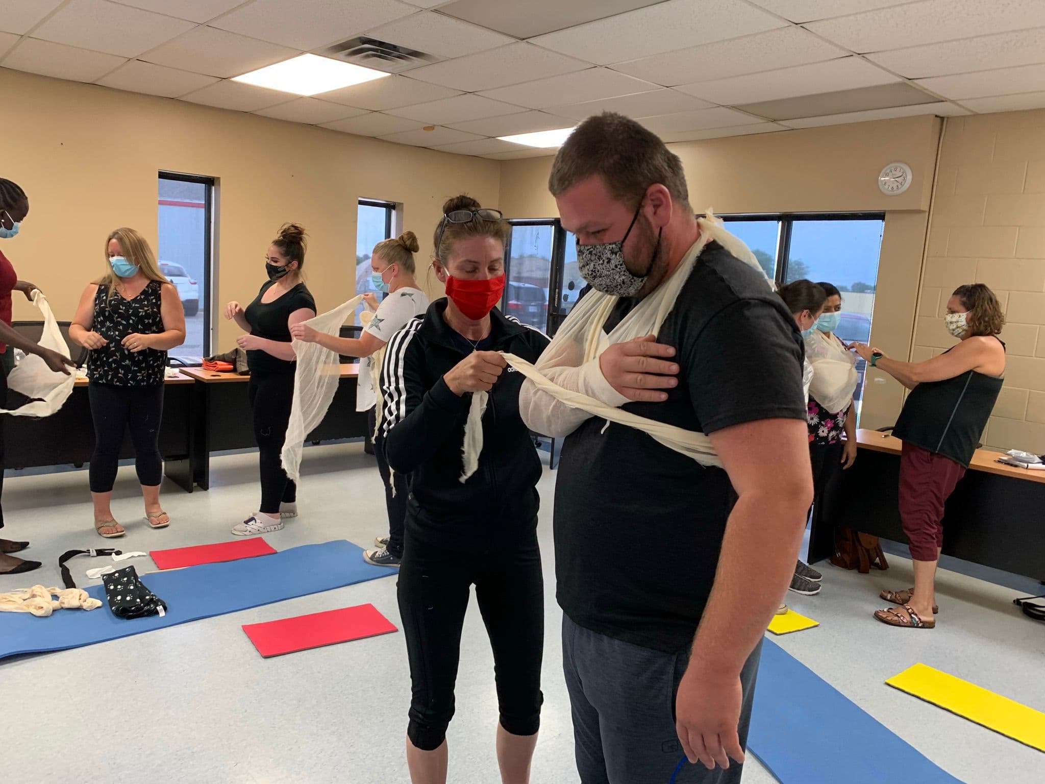 Instructor guiding a participant through a sling and bandage technique in class